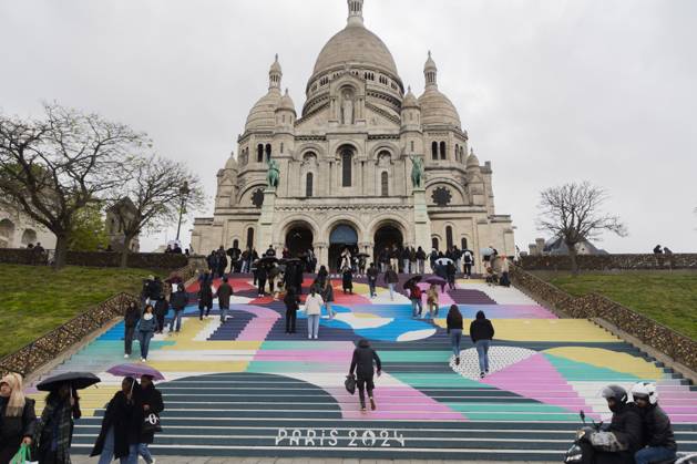 Entertainment Bilder des Tages Paris, France April 19, 2024 - People walk up the stairs leading to the Sacre Coeur basilica decorated with a fresco in Olympic colors as part of the preparations for the Paris 2024 Olympic Games. Less than 100 days remain for the Olympic and Paralympic Games organizers to finalize preparations for the event that will welcome millions of visitors from July 16. OLY, JEUX OLYMPIQUES PARIS 2024, DECORATIONS, FRESQUE, ILLUSTRATION, MONTMARTRE, BASILIQUE DU SACRE COEUR, SPORT, ESCALIERS, MARCHES COLOREES, Copyright: xVincentxIsorex