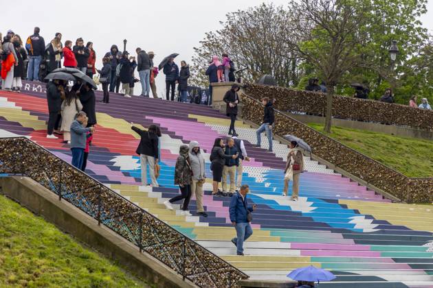 Paris, France April 19, 2024 - People walk up the stairs leading to the Sacre Coeur basilica decorated with a fresco in Olympic colors as part of the preparations for the Paris 2024 Olympic Games. Less than 100 days remain for the Olympic and Paralympic Games organizers to finalize preparations for the event that will welcome millions of visitors from July 16. OLY, JEUX OLYMPIQUES PARIS 2024, DECORATIONS, FRESQUE, ILLUSTRATION, MONTMARTRE, BASILIQUE DU SACRE COEUR, SPORT, ESCALIERS, MARCHES COLOREES, Copyright: xVincentxIsorex