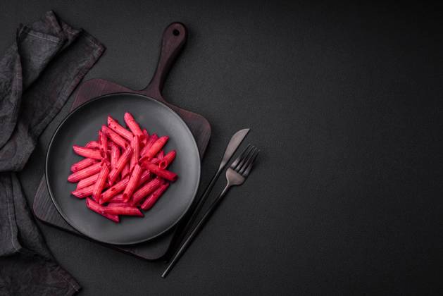 Delicious penne pasta with beets, cheese, salt and spices Delicious penne pasta with beets, cheese, salt and spices on a dark concrete background Copyright: xZoonar.com TetianaxChernykovax 21432865