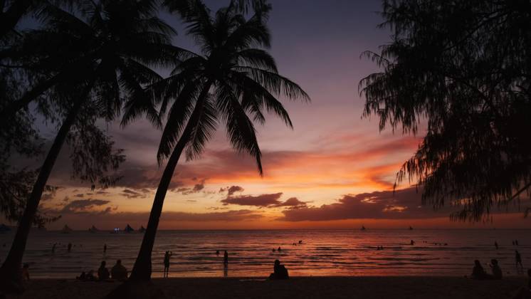 Sunset on beach with people and palms Silhouetted people and palms near sea. Sunset at tropical White beach, Boracay island, Philippines Copyright: xZoonar.com MikhailxKokhanchikovx 21448124