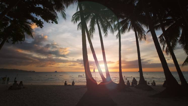 Sunset on beach with people and palms Silhouetted people and palms near sea. Sunset at tropical White beach, Boracay island, Philippines Copyright: xZoonar.com MikhailxKokhanchikovx 21448140