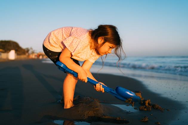 Intently focused, a young child digs in the sand with a blue shovel on the beach, with the evening light casting a soft glow on the activity Intently focused, a young child digs in the sand with a blue shovel on the beach, with the evening light casting a soft glow on the activity. High quality photo ,model released, Symbolfoto Copyright: xZoonar.com AlexandraxTroyanx 21556387 ,model released, Symbolfoto ,property released