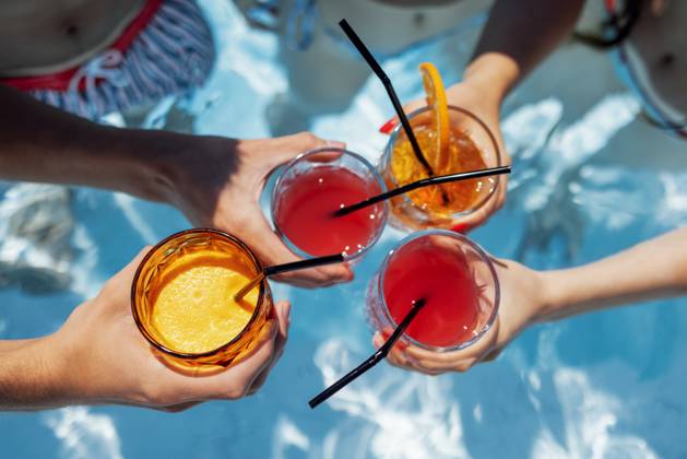 Close-up of female and male hands holding glasses with iced cocktails and clinking them Close-up of female and male hands holding glasses with iced cocktails and clinking them. Friends make festive toast with delicious drinks against background of clear blue pool water. Party, vacation. Copyright: xZoonar.com DashaxPetrenkox 21583449