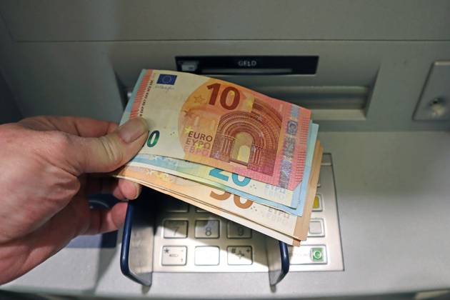 Cash supply from an ATM A person withdraws a large amount of cash in 50, 20 and 10 euro bills from an ATM