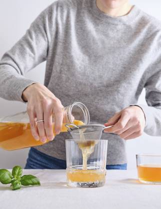 Female model pouring organic homemade komucha from a bottle into a glass Female model pouring organic homemade komucha from a bottle into a glass standing on white background Copyright: xAsyaxNurullinax AN260424-6