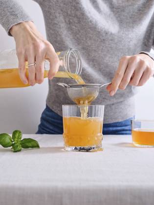 Female model pouring organic homemade komucha from a bottle into a glass Female model pouring organic homemade komucha from a bottle into a glass standing on white background Copyright: xAsyaxNurullinax AN260424-8