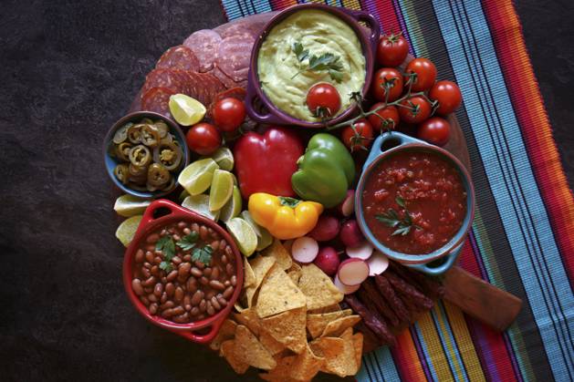 Mexican theme charcuterie board grazing platter with guacamole, salsa, beans, jalapenos, chorizo, and tortilla chips. Mexican theme charcuterie board grazing platter with guacamole, salsa, beans, jalapenos, chorizo, and tortilla chips. Copyright: xMilleflorexImagesx MIL190224-11