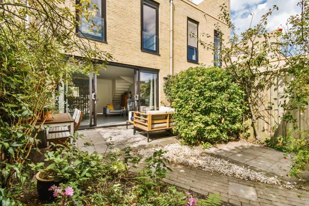 Elegant backyard patio of a modern home featuring stylish outdoor furniture, open sliding doors, and a vibrant garden. Model Released ProCreators_ID5188_167283_012 Copyright: xProxCreatorsx RECORD DATE NOT STATED