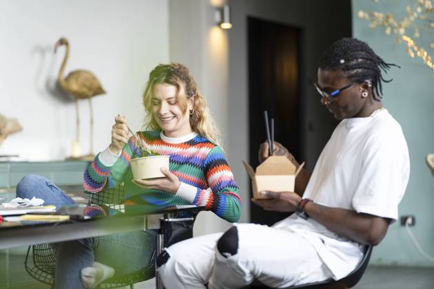 A happy young multiethnic couple takes a break from smart working at home, enjoying a meal together in a cozy, modern interior with nature illustrations Model Released VictorCuenca_ID22085_646426_029 Copyright: xVictorxCuencax RECORD DATE NOT STATED