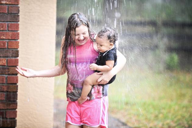 Girl and baby playing in rain, both smiling and enjoying. United States, Florida, Inverness R_YWQX240623D-1468461-01 ,model released, Symbolfoto