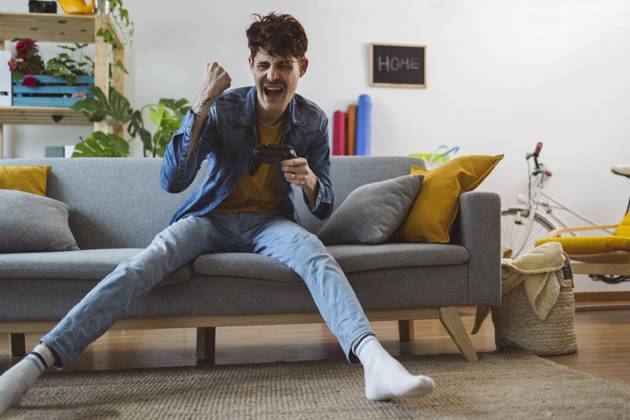 IMAGO Creative, Lifestyle, Gaming Cheerful man winning video game with controller at home model released, Symbolfoto property released, ALZF00282