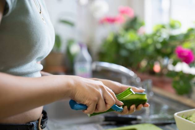 Close-up of young woman peeling vegetables in kitchen model released Copyright: xCulturaxCreativex