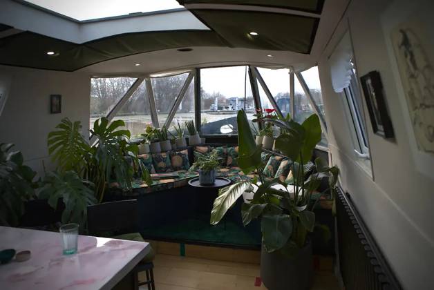Love plants? Stay in London™s first live-in terrarium boat this summer Story from Jam Press (Terrarium Boat) Pictured: The living room. Love plants? Stay in London™s first live-in terrarium boat this summer Are you a plant lover? A water babe? Well, now you can take both to the next level with a stay on a ˜terrarium boat . Moored on a canal in Hackney, London, this life-size ecosystem is made for those who want to get close to nature. The 48.3 sq m boat is decked out with 150 verdant houseplants - making it a perfect live-in oasis. Terrariums are more commonly known to be small, sometimes big, glass enclosures filled with plants, stones and mosses. But this one is a floating, green sanctuary. The two-guest property is co Copyright: xJamxPress @thefloatingterrarium