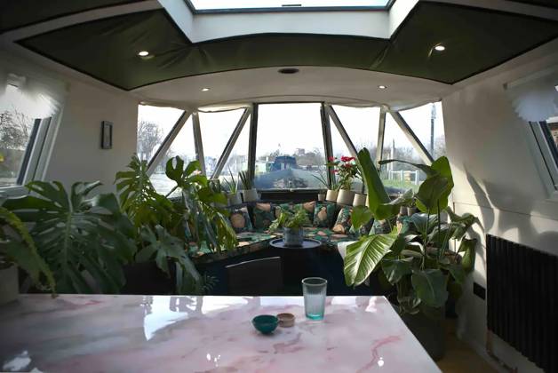 Love plants? Stay in London™s first live-in terrarium boat this summer Story from Jam Press (Terrarium Boat) Pictured: The dining area. Love plants? Stay in London™s first live-in terrarium boat this summer Are you a plant lover? A water babe? Well, now you can take both to the next level with a stay on a ˜terrarium boat . Moored on a canal in Hackney, London, this life-size ecosystem is made for those who want to get close to nature. The 48.3 sq m boat is decked out with 150 verdant houseplants - making it a perfect live-in oasis. Terrariums are more commonly known to be small, sometimes big, glass enclosures filled with plants, stones and mosses. But this one is a floating, green sanctuary. The two-guest property is co Copyright: xJamxPress @thefloatingterrarium