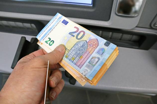 Cash supply from an ATM A person withdraws a large amount of cash in 50 and 20 euro bills from an ATM