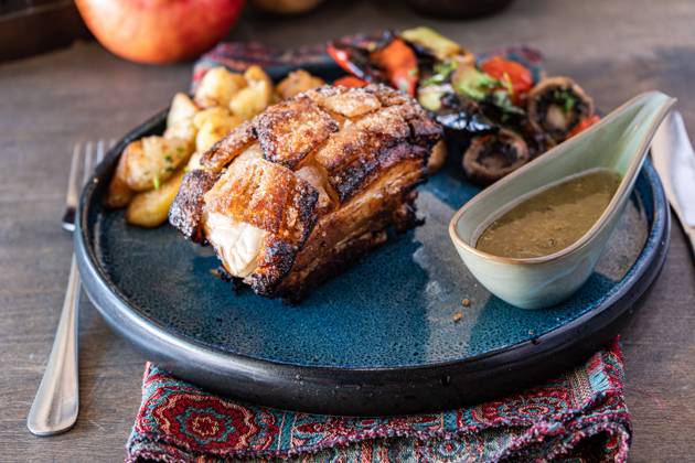 Roast pork loin glazed with a rich honey sauce, accompanied by a colorful salad of grilled vegetables and potatoes, served on a blue ceramic plate with a rustic setting Model Released AnnaBogush_ID22685_661225_002 Copyright: xAnnaxBogushx