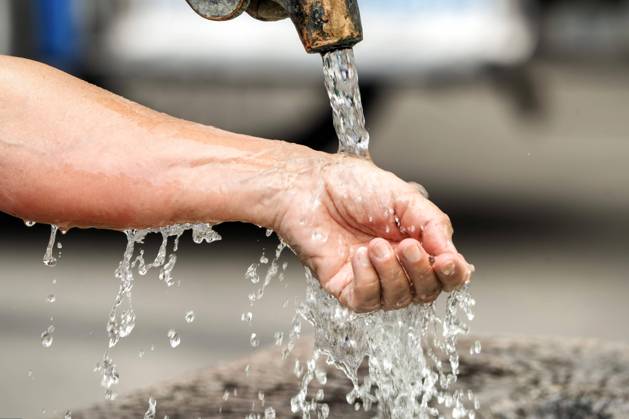 Cooling down at the fountain, woman lets cold water run over her wrist, heat wave, Munich, August 2024 Germany, Munich, August 2024, a woman lets cold water run over her arm and wrist, the summer heat is brutal, the fountain water promises cooling in the heat wave, temperatures over 30 degrees, record heat, summer weather, midsummer, summer, Bavaria,