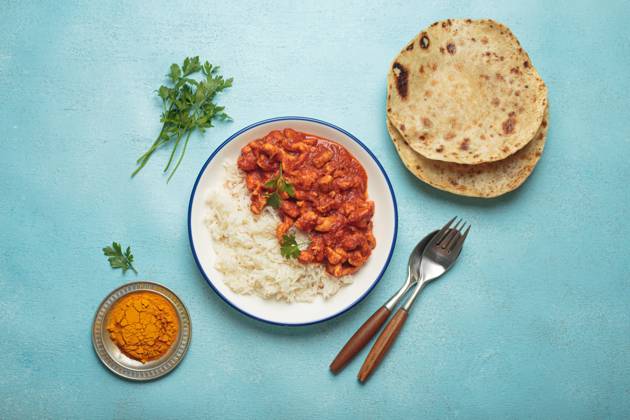 IMAGO Creative, Food, Brot, Naan Indian chicken curry with basmati rice served on plate with chapati flatbread on the side top view Delicious chicken curry with basmati rice, chapati, and cutlery on blue background. Top view shows homemade Indian meal. Spicy and tasty for lunch or dinner Copyright: xZoonar.com OlenaxYeromenkox 22067084