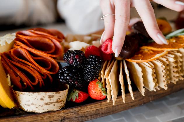 Woman s hand picking a raspberry off charcuterie grazing board San Diego, California, United States R_GPXONO24082198-1521260-01