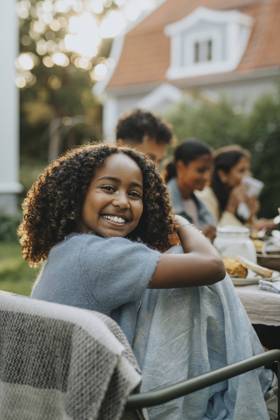 IMAGO Creative, Lifestyle, Feste im Garten #2 Portrait of happy curly hair girl sitting on chair at social gathering in back yard Sweden, Gothenburg, model released, property released Copyright: xMaskotx, MA111558
