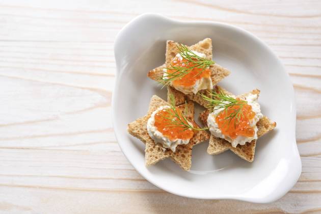 Canapes mit rotem Kaviar auf geröstetem Brot in Sternform mit Sahne und Dillgarnitur auf weißem Teller, heller Holztisch, Kopierraum, Blickwinkel von oben, gewählter Fokus Canapes with red caviar on toasted bread in star shape with cream and dill garnish on a white plate, light wooden table, copy space, high angle view from above, selected focus Copyright: imageBROKER MarenxWinter ibxiqx11040015.jpg