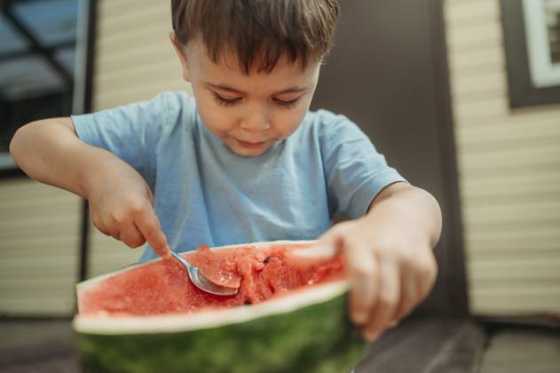 Cute boy eating watermelon with spoon in back yard model released, Symbolfoto, ANAF03630