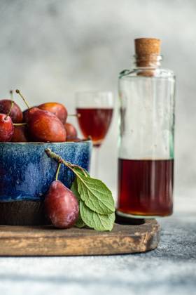 IMAGO Creative, Jahreszeit Sommer, Food, Pflaume A bowl of fresh, organic plums alongside a bottle of homemade plum liqueur, captured from the side. The image highlights ripe plums with vibrant colors and a glass of plum liqueur, suggesting a cozy, autumnal setting. Model Released AnnaBogush_ID23878_692882_013 Copyright: xAnnaxBogushx