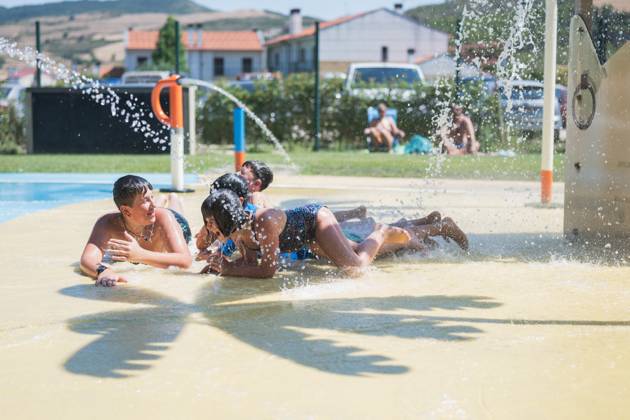 IMAGO Creative, Jahreszeit Sommer, Hitze Kids playing under a water spray in a pool area on a hot summer day, cooling off and splashing. The scene captures children lying prone and discussing excitedly, some looking at each other, engaged in lively conversations. Model Released HodeiUnzueta_ID23816_691396_004 Copyright: xHodeixUnzuetax