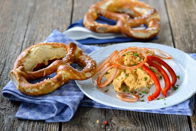 Portion Biergartenkaese Bayerische Käsespezialität - Portion Obazter mit Zwiebelringen und Brezel; A Bavarian snack: So called Obazda - cheese specialty made of melted camembert with cream cheese and butter, onions, a splash of beer and some spices - served with a pretzel on a white plate Copyright: xZoonar.com KarlxAllgaeuerx 8477822