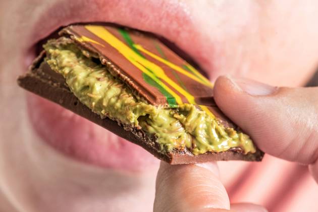 Woman enjoys a piece of Dubai chocolate with kunafa and pistachio cream filling, Hype about Dubai chocolate, Munich, November 2024 Germany,Munich, November 2024, Woman enjoys a piece of Dubai chocolate with kunafa and pistachio cream filling, Orient Delight brand, Made in U A E , United Arab Emirates, which includes Dubai, Hype