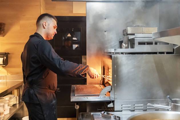 An expert chef serving meals in the bustling kitchen of a restaurant, surrounded by steam due to the use of the grill in the kitchen Model Released PaulaBerezo_ID24490_709733_007 Copyright: xPaulaxBerezox RECORD DATE NOT STATED