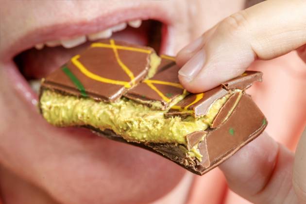 Woman enjoys a piece of Dubai chocolate with kunafa and pistachio cream filling, Hype about Dubai chocolate, Munich, November 2024 Germany, Munich, November 2024, Woman enjoys a piece of Dubai chocolate with kunafa and pistachio cream filling, Orient Delight brand, Made in U A E , United Arab Emirates, which includes Dubai, Hyp