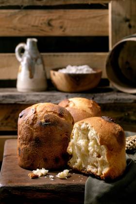 Hausgemachtes traditionelles italienisches Brioche-Weizenbrot ganz und halb Group of homemade traditional italian brioche wheat bread with cheese inside, whole and half. Standing on wooden table in rustic kitchen with kitchen utensil at background. Copyright: xZoonar.com NATASHAxBREENx 22664214