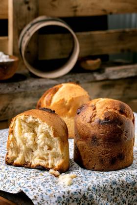 Hausgemachtes traditionelles italienisches Brioche-Weizenbrot ganz und halb Homemade traditional italian brioche wheat bread with cheese inside, whole and half. Standing on wooden table floral tablecloth in rustic kitchen with kitchen utensil at background. Copyright: xZoonar.com NATASHAxBREENx 22664215