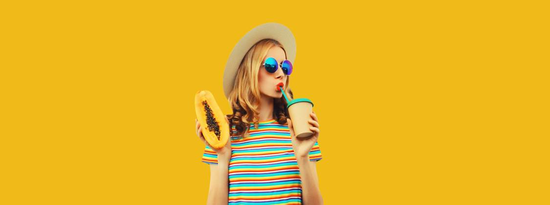Sommer Porträt der stilvollen jungen Frau mit Papaya-Frucht trinken frischen Saft auf gelbem Hintergrund Summer portrait of stylish young woman with juicy papaya fruit drinking fresh juice looking away in straw hat, sunglasses on colorful yellow studio background Copyright: xZoonar.com VeronikaxKornevax 22708811