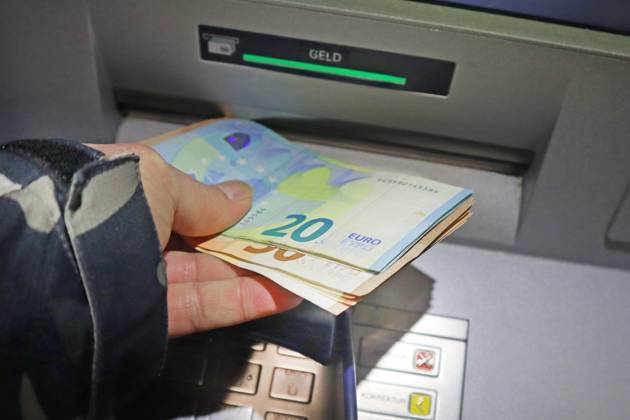 Cash supply from an ATM A person withdraws cash in 50 and 20 euro bills from an ATM