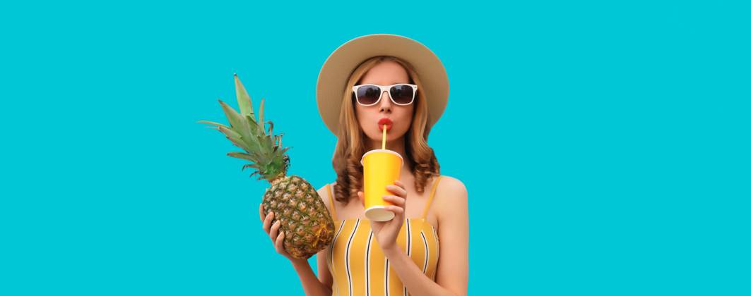 Sommer Porträt der stilvollen jungen Frau trinken frischen Saft mit Ananas Obst auf blauem Hintergrund Summer bright portrait of stylish young woman drinking fresh juice holding pineapple fruit in straw hat, sunglasses on colorful blue studio background ,model released, Symbolfoto Copyright: xZoonar.com VeronikaxKornevax 22725110 ,model released, Symbolfoto ,property released