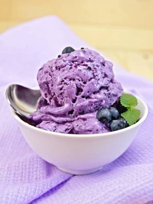 Heidelbeereis mit Minzblättern in einer Schale mit Beeren, Minze und Löffel auf einem Hintergrund aus lila Stoff und Holzbrettern Blueberry ice cream with mint leaves in a bowl with berries, mint and spoon on a background of purple cloth and wooden boards Copyright: imageBROKER kostrez ibxiqx12413058