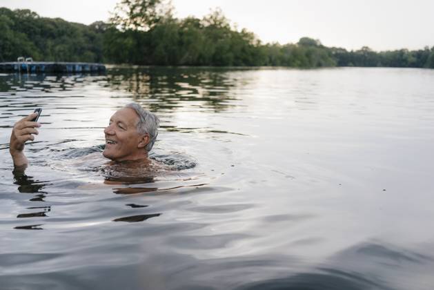 Senior man using cell phone in a lake model released, Symbolfoto, GUSF01807
