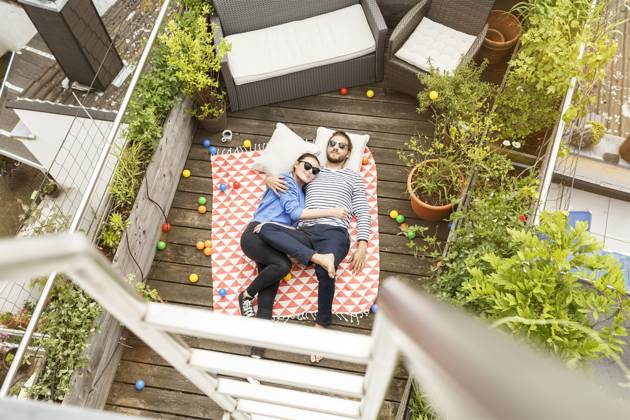 Young couple relaxing on their balcony, lying on blanket with arms around model released, Symbolfoto property released, PESF01173