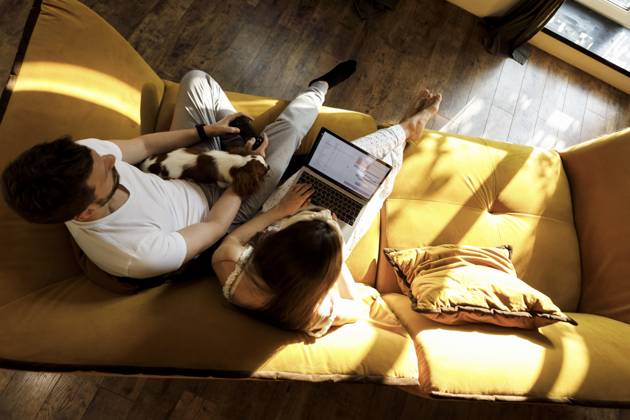 IMAGO Creative, Lifestyle, Gaming A woman works on her laptop while a man plays a console with a dog on his lap in a living room model released, Symbolfoto property released, EHAF00440