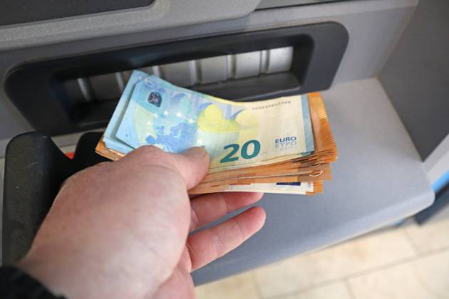 Cash supply from an ATM A person withdraws cash in 50 and 20 euro bills from an ATM
