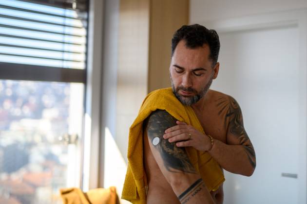 Diabetic man checking his CGM sensor after shower. Diabetic man checking his CGM sensor on arm after shower. model released