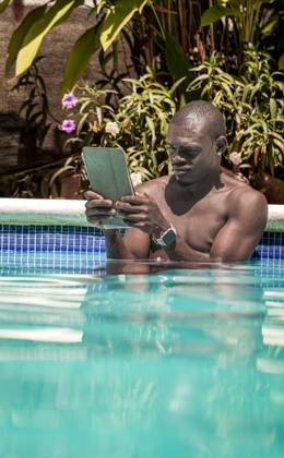 IMAGO Creative, Jahreszeit Sommer, Hitze Black man working on a tablet while relaxing in a tropical pool Las Terrenas, Samaná Province, Dominican Republic R_JURA250318-1685417-01 ,model released, Symbolfoto