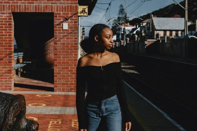 IMAGO Creative, Jahreszeit Sommer, Sommerferien Retro image of a young black female waiting for a train South Africa, Western Cape, Cape Town CR_YNJN250325-1691016-01 ,model released, Symbolfoto