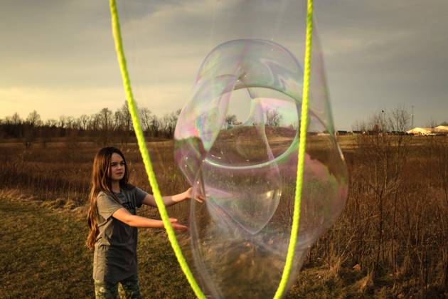 IMAGO Creative, Jahreszeit Sommer, Sommerferien Tween girl popping giant bubble in sunny field Wooster, Ohio, United States CR_JOKU250331B-1684840-01 ,model released, Symbolfoto