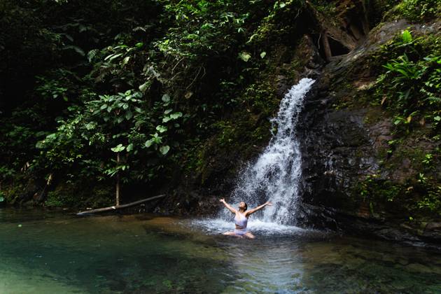Young woman enjoying and stretching arms in a natural pool under a waterfall in the Choco Andino rainforest, Ecuador. This image captures the spirit of ecotourism and adventure in a biodiverse tropical landscape. Model Released Cardellach_ID27637_793647_017 Copyright: xCardellachx RECORD DATE NOT STATED