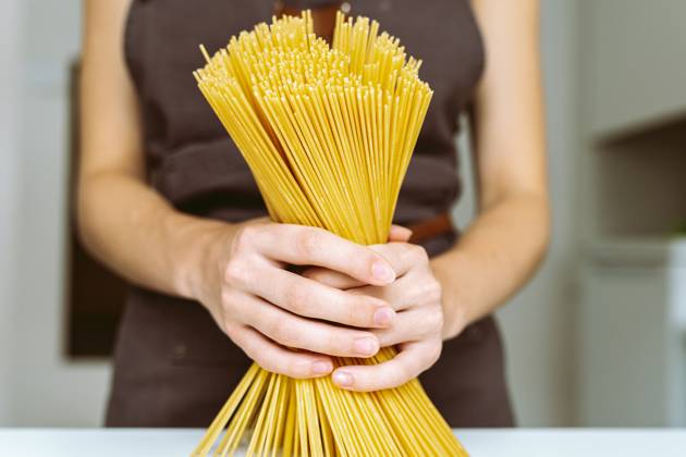 Koch mit Spaghetti in der Hand Woman in brown chef s apron holding spaghetti close-up. Chef holding spaghetti (License=RF) ,model released, Symbolfoto Copyright: xZoonar.com LarysaxStefaniukx 23639107 ,model released, Symbolfoto ,property released