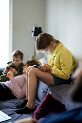 IMAGO Creative, Lifestyle, Gaming Full length of girl playing games on smart phone while sitting on sofa at home Sweden, Stockholm, model released, property released Copyright: xMaskotx , MA118172 MA118172