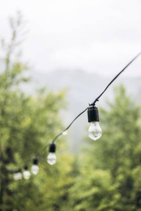 MR_ID29414_21446_OlhaHusonka.jpg String lights hang delicately against a lush, green mountain backdrop, capturing the serene ambiance of a rainy morning. Gentle raindrops settle on the bulbs Model Released HannaYakimenko_ID29414_1000839_008 Copyright: xHannaxYakimenkox